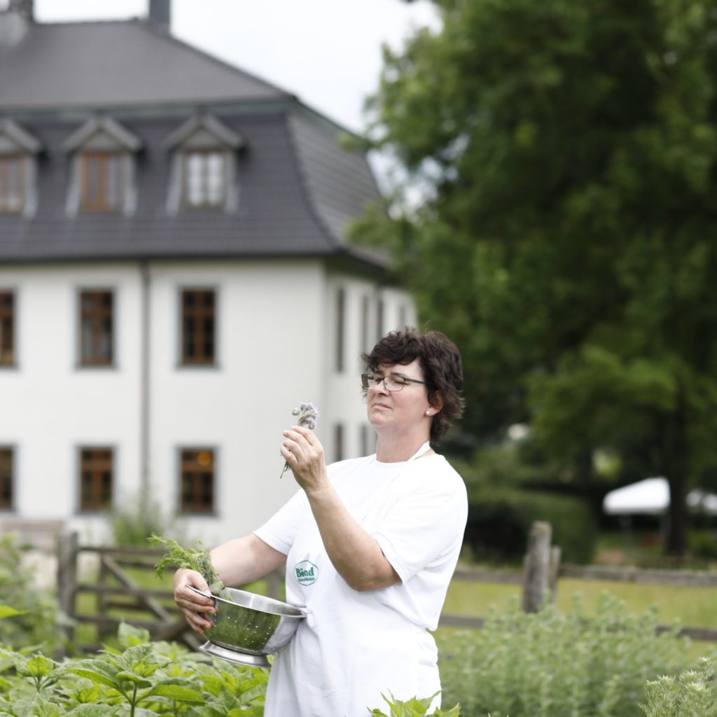 Frau im Kräutergarten mit Kräutern