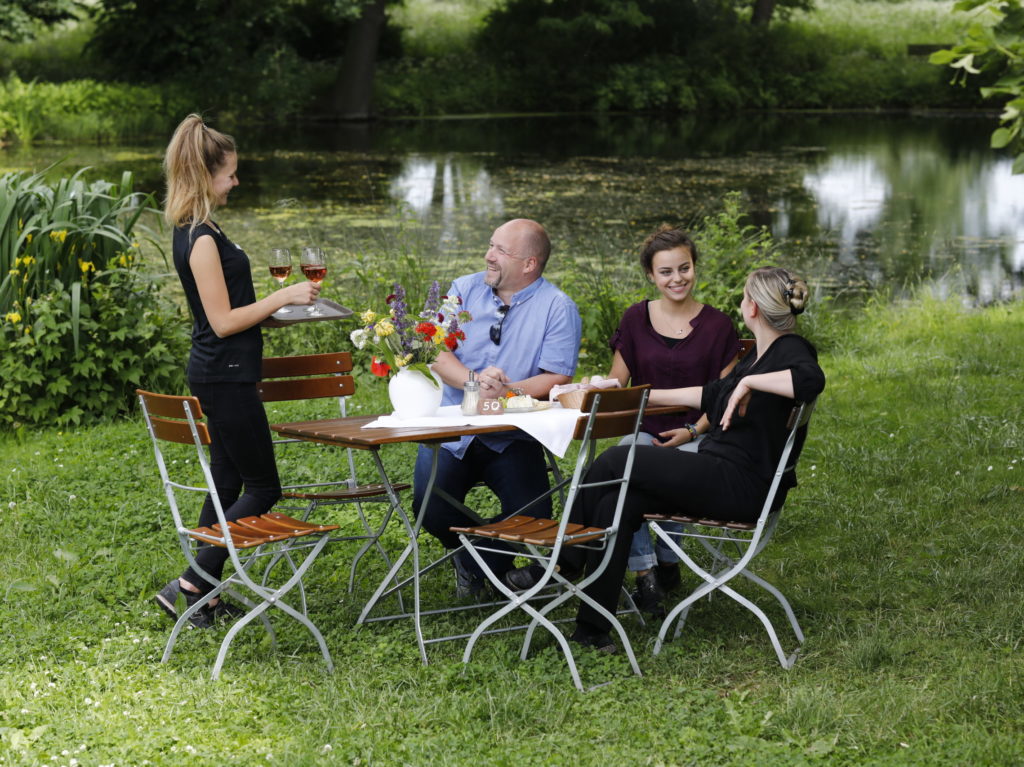 Menschen am Tisch vor Teich